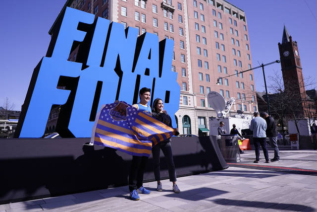 Fans pose with a Final Four logo before a college basketball game during the Final Four round of the NCAA tournament at Lucas Oil Stadium in Indianapolis on Saturday.