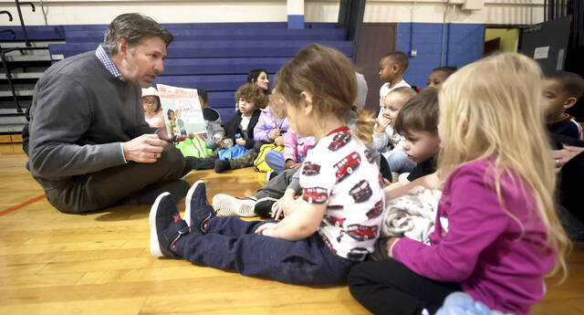 Tony Brooks reads a story to a group of children in the Wilkes-Barre CYC as part of the Holiday Resource Fair on Friday.
                                 Fred Adams | For Times Leader