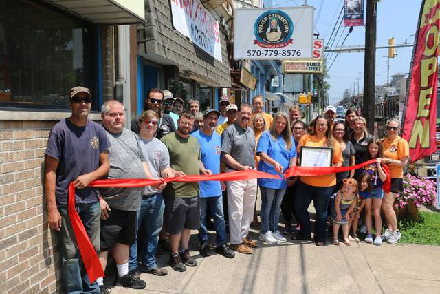 Plymouth Alive President Alexis Eroh, holding a plaque, and Plymouth Mayor Frank Coughlin, stand alongside Polish Connection Owner Marie Ondish as she cuts a ribbon to mark the reopening of the business that was closed when a fire hit the building on East Main Street on Easter Sun day.
Attending the ceremony were members of Plymouth Alive, and firefighters representing all three Plymouth Hose Companies who responded to the fire with speed and professionalism to save the building for the Grand Re-opening.
Courtesy of Scott Cannon